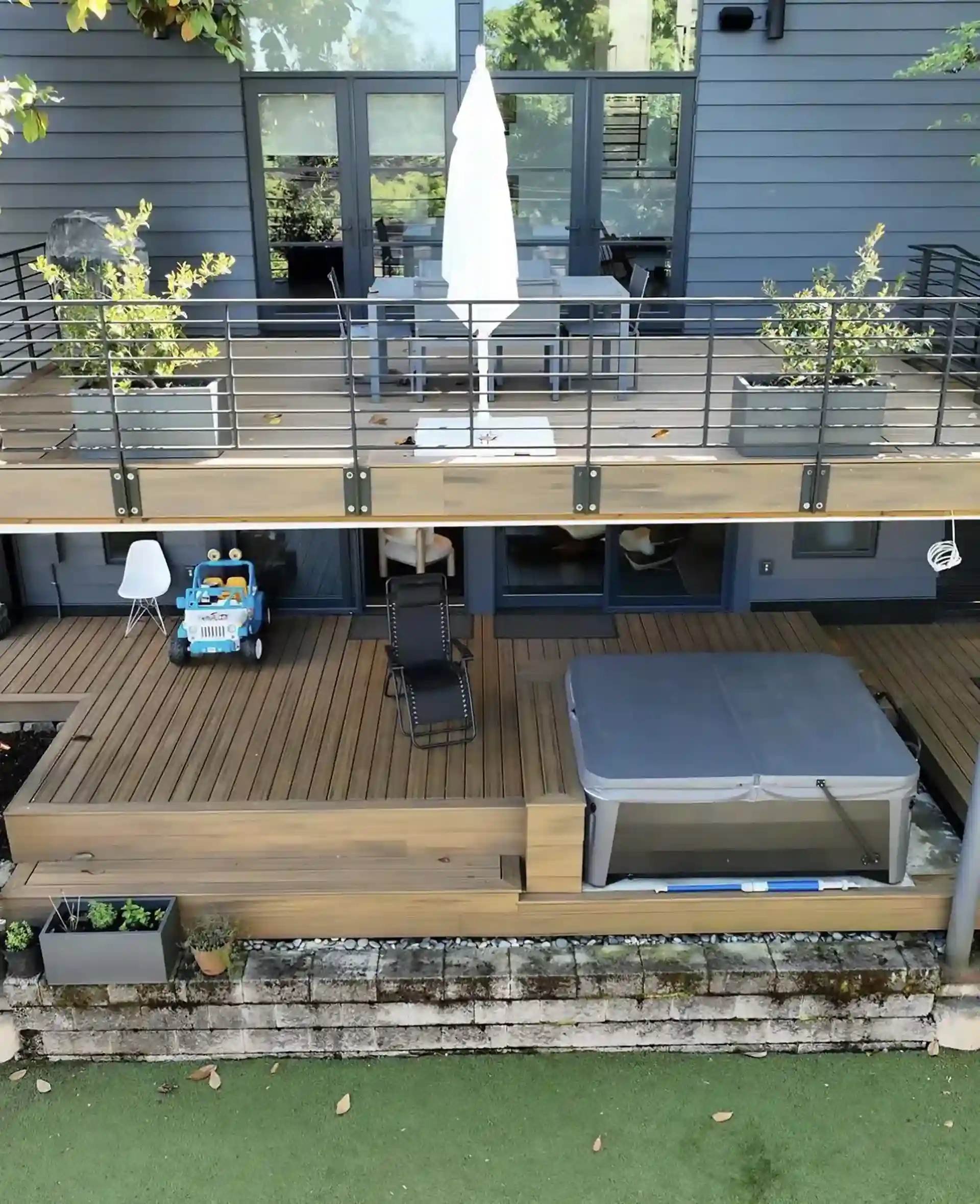 photo of a multi-level deck with an outdoor dining room on the upper level, and a relaxation zone on the lower level with a hot tub.